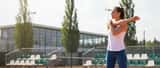 Active woman stretching on a tennis court, preparing for play after a shoulder injury