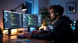 Informaticien travaillant de nuit sur double écran dans un bureau sombre, illustration des faux freelances nord-coréens