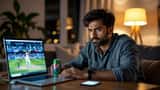 Aficionado de origen sudasiático mirando cricket en laptop de madrugada con estrés visible y ojeras