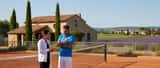 Joueur de tennis amateur examinant son coude avec un médecin du sport sur un court extérieur