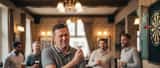 British darts player holding his elbow in discomfort after throwing at a pub oche during a Premier League match