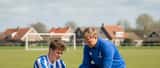 Nederlandse amateurvoetballer krijgt enkelblessure behandeld door sportarts op voetbalveld