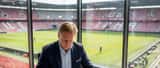 Nederlandse sportadvocaat bekijkt voetbalcontract aan bureau met stadion op achtergrond