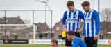 Amateurvoetballer geblesseerd aan enkel op grasveld met bezorgde teamgenoten