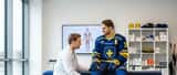 Idrottsmedicinsk läkare undersöker en ishockeyspelares knä i en modern klinik