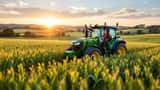 Tracteur moderne roulant dans les champs verdoyants de la ferme Diddly Squat au coucher du soleil