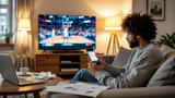 Frustrated man checking sports betting app on phone with NBA game playing on television in background