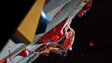 Competitive climber ascending a wall at an indoor climbing championship