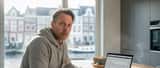 Bezorgde Nederlandse man bekijkt verdachte e-mail op laptop aan keukentafel in Rotterdam