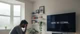 Person holding PlayStation controller in front of error screen on TV