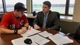 Baseball player reviewing contract documents with agent at conference table