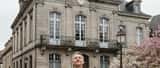 Homme en costume sombre à l'extérieur d'un palais de justice suisse à Muttenz, tenant des documents juridiques, lumière de printemps