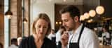 British woman showing allergen information on a menu to a restaurant waiter in a UK restaurant