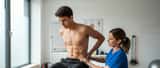Physiothérapeute examinant le dos d'un jeune sportif en salle de consultation médicale