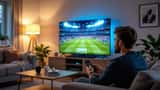 Man justerar smart-TV-inställningar i vardagsrum med Premier League-match på skärmen