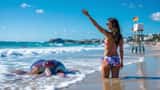 Femme montrant une piqûre de galère portugaise sur la plage de Biarritz, physalie dans l'eau et drapeau rouge en arrière-plan