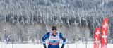 Langrennsløper i mål på Lygna skianlegg i Norge, vinterlandskap med birketrær