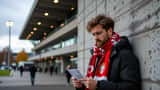 Adepto português do Torreense a verificar bilhete e cartão de embarque no exterior do estádio de Lillestrøm