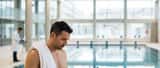 Nageur de haut niveau au bord d'une piscine olympique, consultant un médecin du sport sur sa reconversion