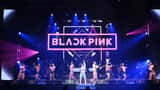 Espetáculo K-Pop com bailarinas em palco iluminado com luzes cor-de-rosa e azul num concerto em Portugal