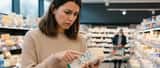 Une consommatrice examine l'étiquette d'un gorgonzola dans un supermarché français