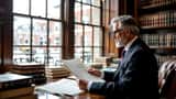 Solicitor examining newspaper columns and legal documents on an oak desk in a London legal office