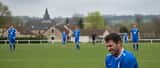 Footballeur amateur français assis au bord du terrain tenant son ischio-jambier blessé