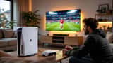 IT-tekniker sjekker nettverkstilkobling til PS5 i norsk stue med fotballspill på TV-skjermen