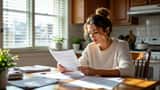 Woman reading an eviction notice at a kitchen table with lease documents and bills spread out