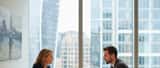 British employment lawyer consulting client in modern London office, documents and laptop