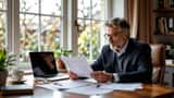 Professional reviewing redundancy documents and pension statements at a home office desk in London