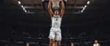 Jeune basketteur français en plein match NBA, en plein élan athlétique