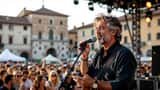 Musicista italiano sul palco di un festival estivo all'aperto in Puglia 2026
