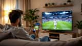 Australian man watching Serie A football match on TV while checking sports betting app on smartphone