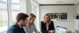 British couple reviewing mortgage documents at kitchen table with financial advisor