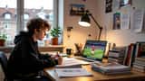 Dansk teenager laver lektier ved skrivebord med fodboldkamp på computeren
