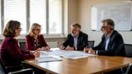 Réunion de copropriétaires à Toulouse autour d'un plan pluriannuel de travaux, documents et plans architecturaux sur la table