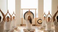 Kundalini Yoga class in Los Angeles with students in white clothing performing mudra meditation led by a South Asian female teacher