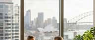 Wealth management consultation in a Sydney high-rise office with harbour light, adviser and client at a timber desk