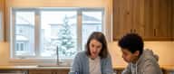 Tutrice expliquant une équation de maths à un élève à une table de cuisine dans une maison de banlieue à Montréal