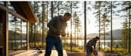 Tømrer måler tømmer i et dansk parcelhus under renovering med synlige spær og naturligt dagslys