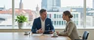 Dansk virksomhedsejer mødes med en professionel revisor ved et skandinavisk skrivebord med dokumenter og laptop