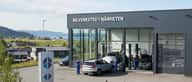 Norsk bilmekaniker inspiserer undersiden av en bil på en hydraulisk løftebukk i et moderne verksted
