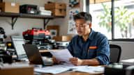Small business owner reviewing purchase invoices and tax documents at a desk in a suburban Melbourne office