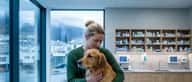 Kvinne holder en golden retriever på undersøkelsesbordet hos veterinæren i Bergen