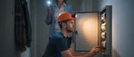 Elektriker im Notdienst repariert Sicherungskasten in einem österreichischen Wohnhaus bei Nacht