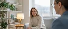 Norsk kvinne i en lys, minimalistisk terapi-kontorsetting i Oslo med psykolog som tar notater
