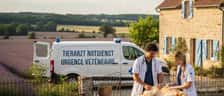 Besorgte Hundebesitzerin hält ihren Hund während der Untersuchung durch einen Tierarzt in einer Notdienstklinik bei Nacht
