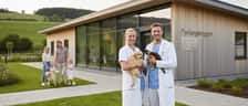 Dansk dyrlæge i blå kittel undersøger en golden retriever hvalp på en veterinærklinik om aftenen