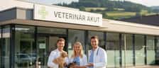 Orolig husdjursägare med en liten hund insvept i en filt utanför en veterinär akutklinik på kvällen